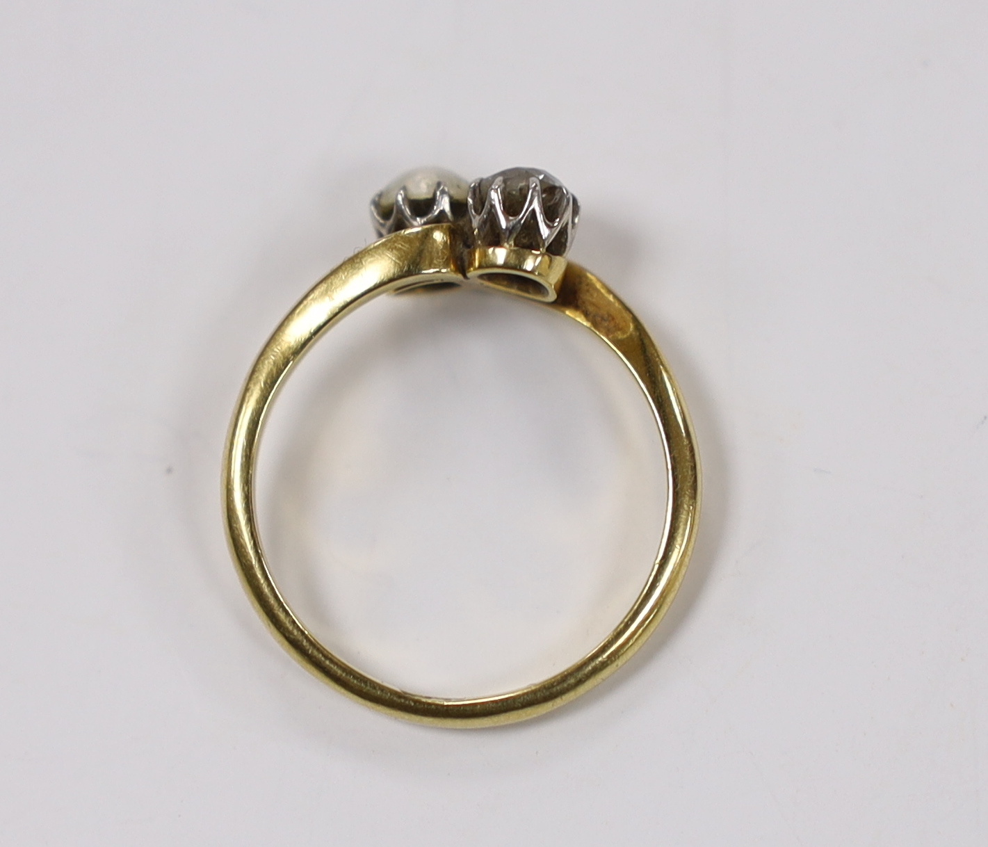 An 18ct, single stone diamond and single stone cultured pearl set crossover ring, size L/M, gross weight 2.6 grams.